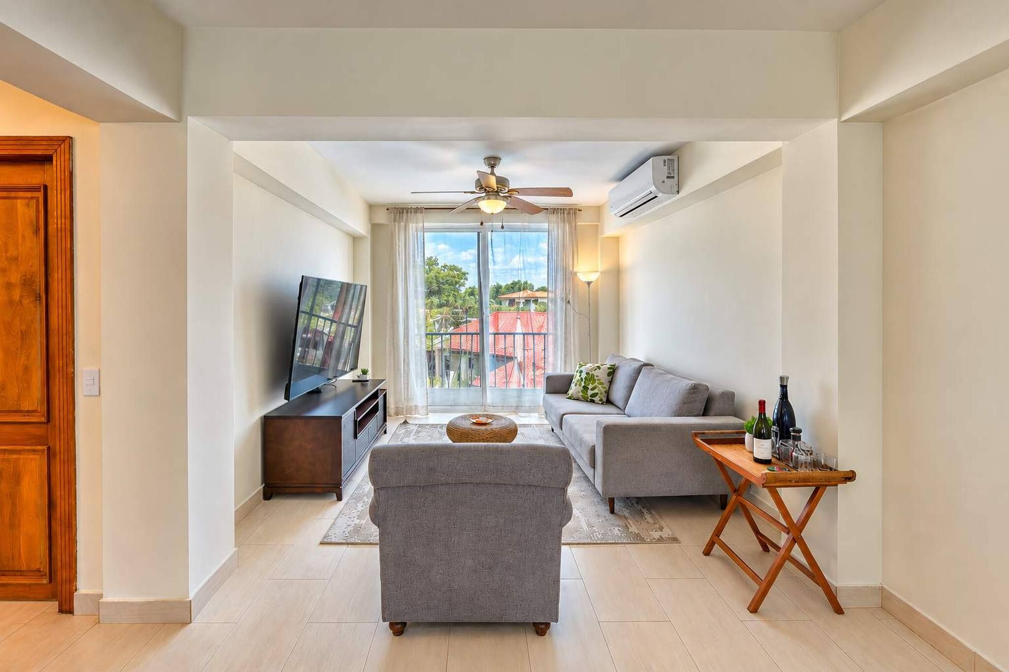 Una sala moderna con sofá, reposapiés y televisor sobre un mueble.