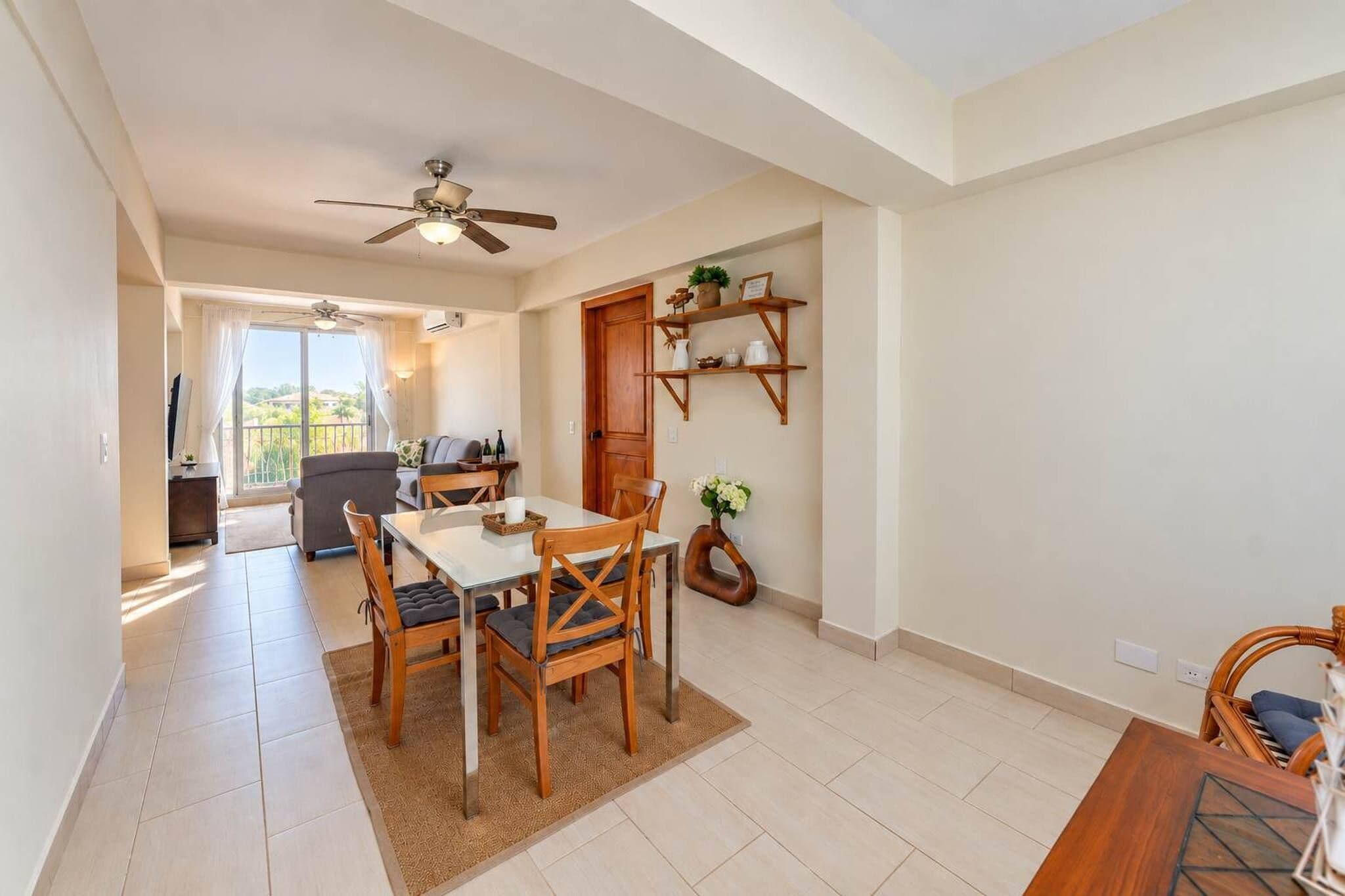 Un coin repas avec une table et des chaises, un ventilateur de plafond et une vue par la fenêtre.
