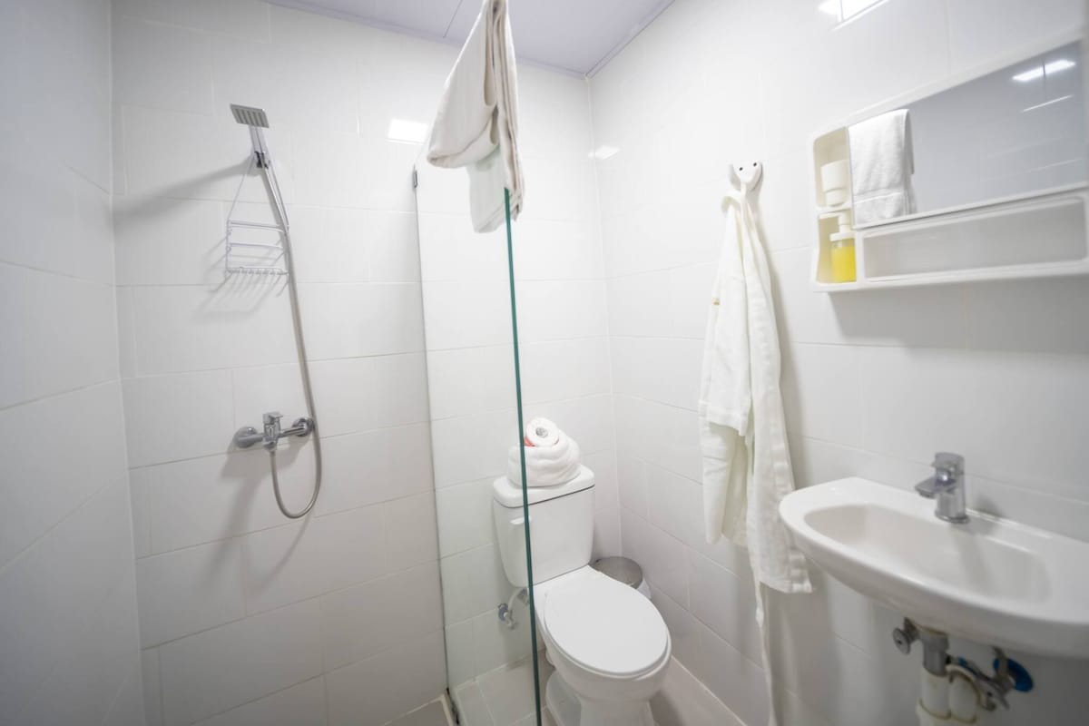 A modern bathroom with a glass-enclosed shower, a toilet, and a sink with a mirror above it.