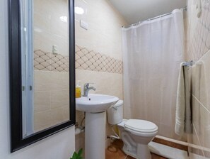 A bathroom with a white sink, toilet, and shower curtain. - Room-getaway Room With Shared Jacuzzi in (Sosúa)