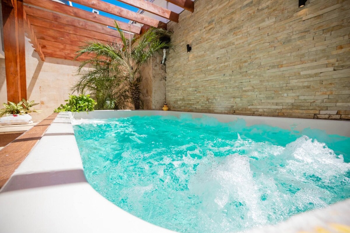 A swimming pool with clear water, surrounded by a wooden deck and a brick wall.