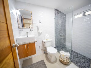 Ein modernes Badezimmer mit Waschbecken, Toilette und Dusche, alles in Weiß.