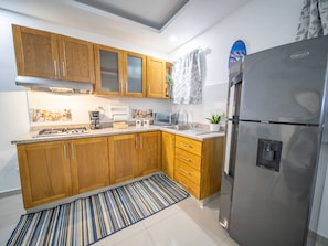 Een moderne keuken met houten kastjes, een roestvrijstalen koelkast, een magnetron en een gasfornuis.
