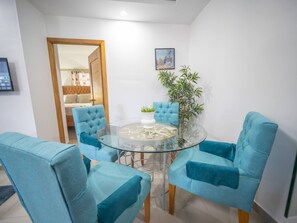 Un espace repas moderne avec une table en verre entourée de quatre chaises bleues à revêtement rembourré.