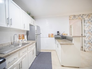 A kitchen with white cabinets, a stainless steel sink, a refrigerator, and a microwave. - Affordable 1BR APT in Sosua Center - Strip Zone (Sosúa)