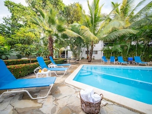 A swimming pool with blue lounge chairs and a wicker basket with towels. - 2BR APT in Sosua Center Strip Zone (Sosúa)
