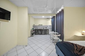 A hotel room with a bed, a desk, a chair, a small kitchenette, and a bathroom. - Cheap Hotel Room in Sosua Strip! (Sosúa)