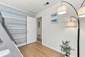 A hallway with a patterned wall, a door, a framed picture, and a potted plant. - Single-Story 4BR · King Suite · Treehouse & Deck (Pleasanton)