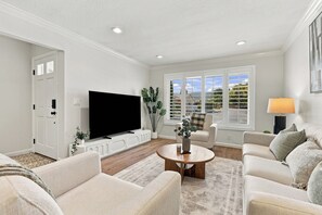 A living room with a flat-screen TV, two sofas, a coffee table, and a window with blinds. - Single-Story 4BR · King Suite · Treehouse & Deck (Pleasanton)