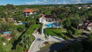 A residential area with a house featuring a swimming pool, surrounded by lush greenery and palm trees. - Hispaniola Villa No26 Near Sosua Beach (Sosúa)