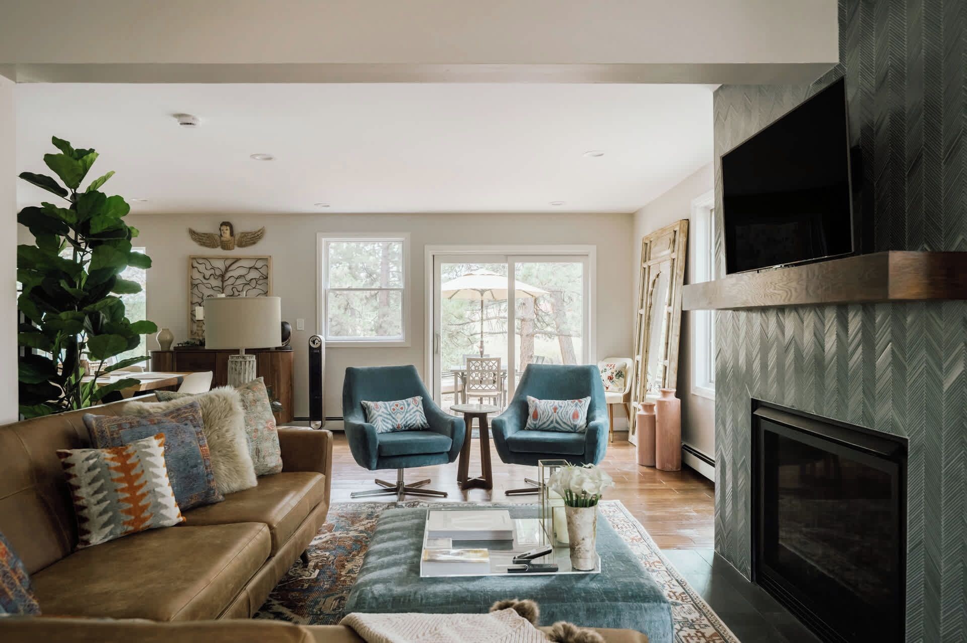 A living room with a fireplace, a sofa, two armchairs, a coffee table, and a large plant.