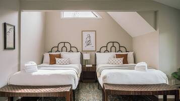 A hotel room with two beds, a skylight, a patterned carpet, and a framed artwork on the wall.