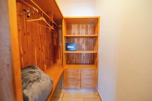 A small, compact room with a bed, wooden wardrobe, and a shelf with a camera. - Luxury 2BR Villa in Ocean Village by Santa Fe (Sosúa)