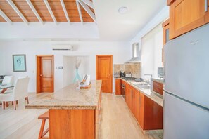 A modern kitchen with wooden cabinets, granite countertops, and a built-in oven. - Luxury 2BR Villa in Ocean Village by Santa Fe (Sosúa)