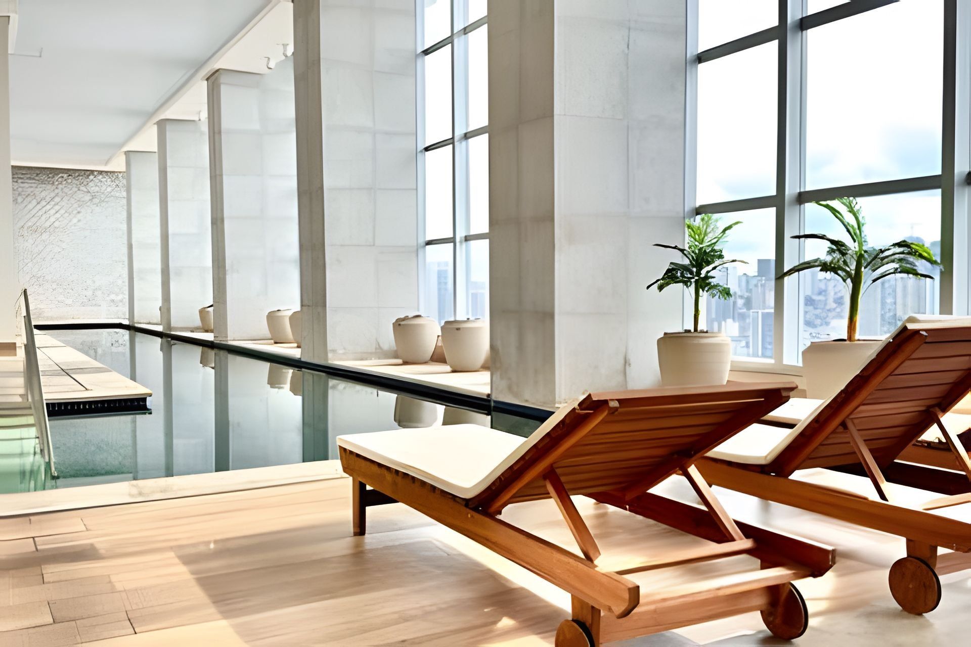 Un área de piscina interior moderna con sillones de descanso y plantas en macetas.