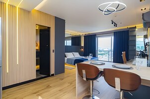 Quarto de hotel moderno com uma cama grande, área de refeições e vista para a cidade.