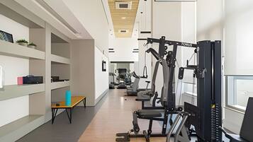 A gym with exercise equipment, wooden floors, and white walls.