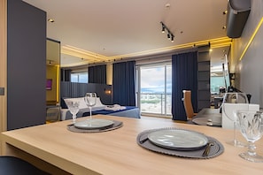 Quarto de hotel moderno com área de refeições, cama e vista da cidade.