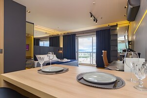 Quarto de hotel moderno com área de refeições, cama e vista da cidade.