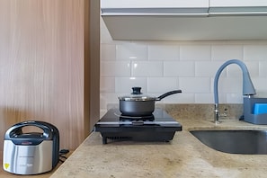 A kitchen with a gas stove, a kettle, and a sink with a blue faucet. - Prime Studios Centro Osasco15min Alpha (Osasco)