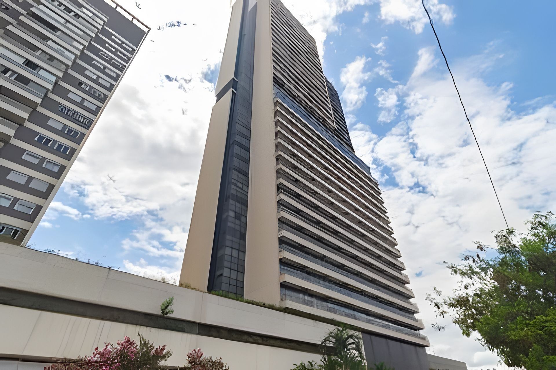 Un edificio alto y moderno con una estructura vertical destacada y una serie de ventanas horizontales.