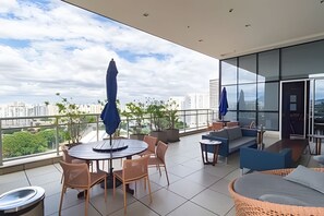 Un espace extérieur moderne aménagé avec une table ronde et des chaises, un canapé et un grand parasol.