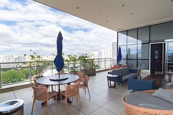Un balcon extérieur moderne avec une table ronde, des chaises et un canapé.