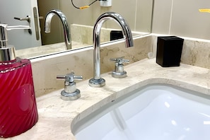 Une salle de bain avec un grand miroir, un lavabo et deux robinets.