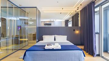 Una habitación de hotel moderna con una cama grande, un separador de vidrio y vistas a la ciudad.