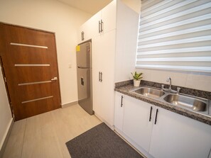 A kitchen with a double sink, a refrigerator, and a wooden door. - Stylish Luxury Villa in Sosua- 5BR Suites! (Sosúa)