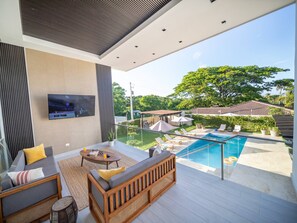 Uma área moderna para atividades ao ar livre, com piscina, assentos e uma tela de televisão.
