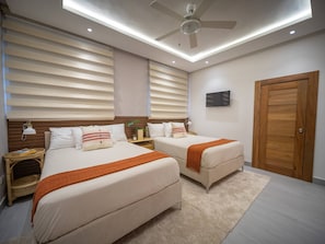 Ein modernes Schlafzimmer mit zwei Betten, einem Deckenventilator und einem Fernseher.