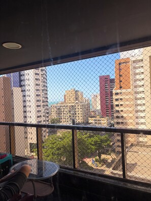 A balcony with a chain-link fence, a round table, and a chair. - Apartment on the beachfront in Fortaleza (Fortaleza)