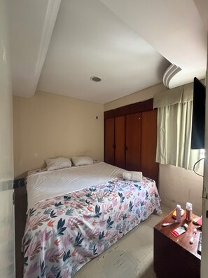 A bedroom with a bed, a wardrobe, a bedside table with toiletries, and a window with curtains. - Apartment right on the beach in Fortaleza (Fortaleza)