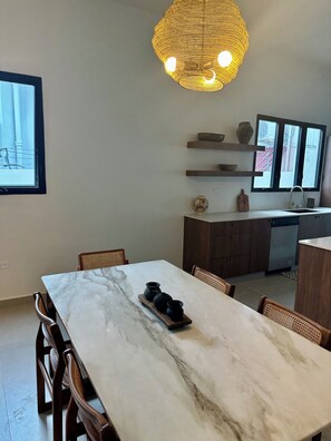 A modern kitchen with a marble countertop, wooden cabinets, and a hanging light fixture. - Organic Modern Retreat in San Juan with Private Patio (San Juan)
