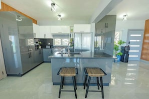 A modern kitchen with a central island, bar stools, and built-in appliances.