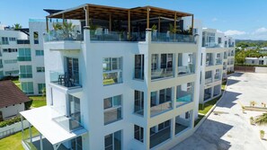 Un hôtel à plusieurs étages doté de balcons, de grandes fenêtres et d’une terrasse sur le toit.
