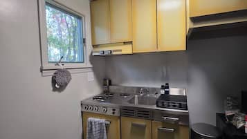 Cocina compacta con estufa a gas, lavamanos y electrodomésticos de acero inoxidable.