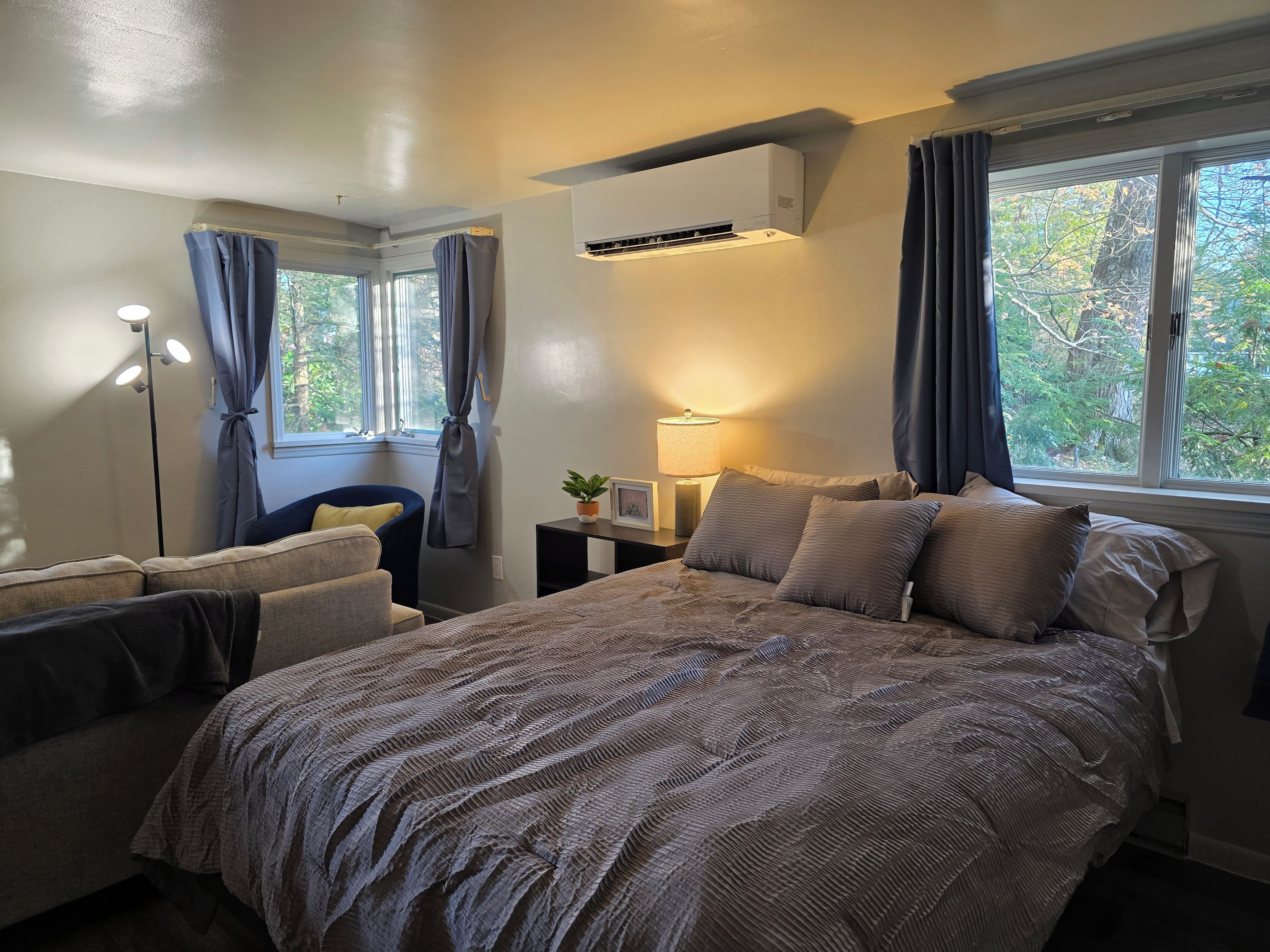 Un dormitorio con cama, mesitas de noche, lámpara y ventana con cortinas.
