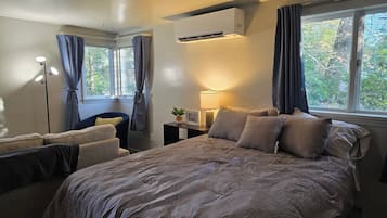 Un dormitorio con cama, mesitas de noche, lámpara y ventana con cortinas.