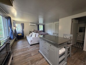 Quarto compacto com cozinha compacta, sofá, mesa de jantar e cama.