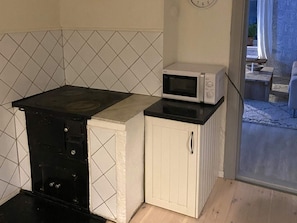 A compact kitchen with a black stove, a microwave, and white cabinetry. - 4 Person Holiday Home in Garphyttan (Garphyttan)
