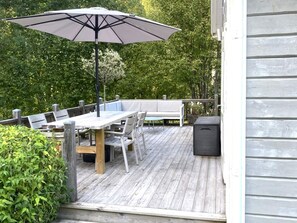 An outdoor deck with a wooden table, chairs, a bench, and a large umbrella. - 4 Person Holiday Home in Garphyttan (Garphyttan)