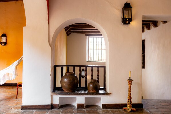 A hallway with a bench, two vases, a candle, and a window with barred glass. - Gorgeous house for rent in Cartagena, Colombia (Cartagena de Indias)