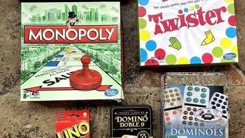 Uma coleção de jogos de tabuleiro, incluindo Monopoly, Twister, UNO, Dominó e um jogo de viagem Rubi-Q.