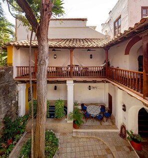 A courtyard with a tiled roof, wooden balcony railings, and a table with chairs. - Gorgeous house for rent in Cartagena, Colombia (Cartagena de Indias)