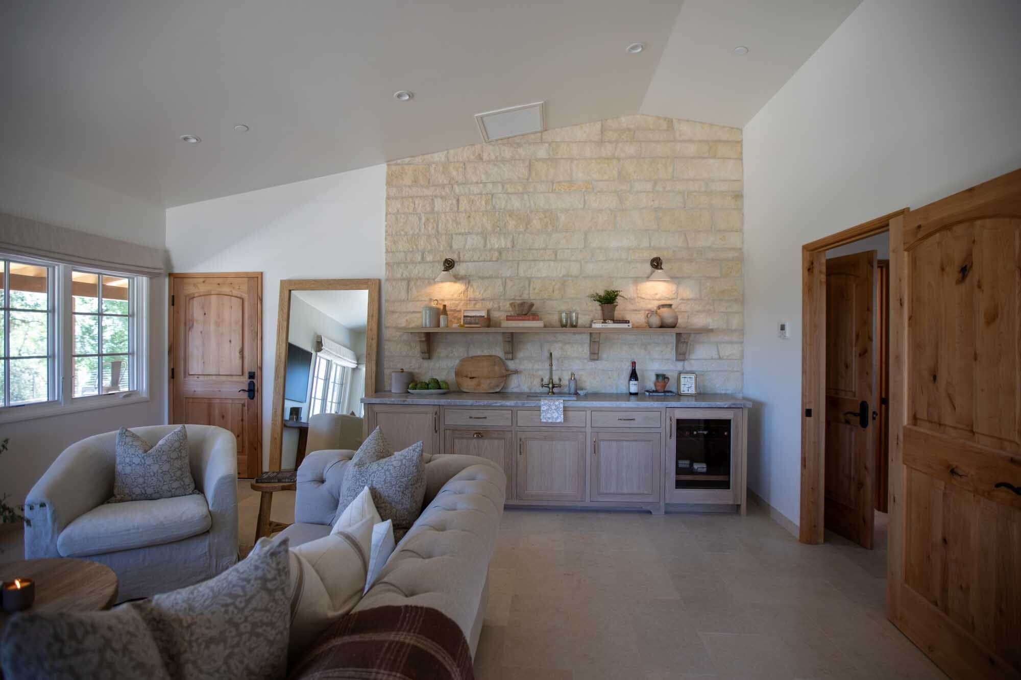 A spacious living area with a stone wall, wooden cabinets, and a built-in kitchen.