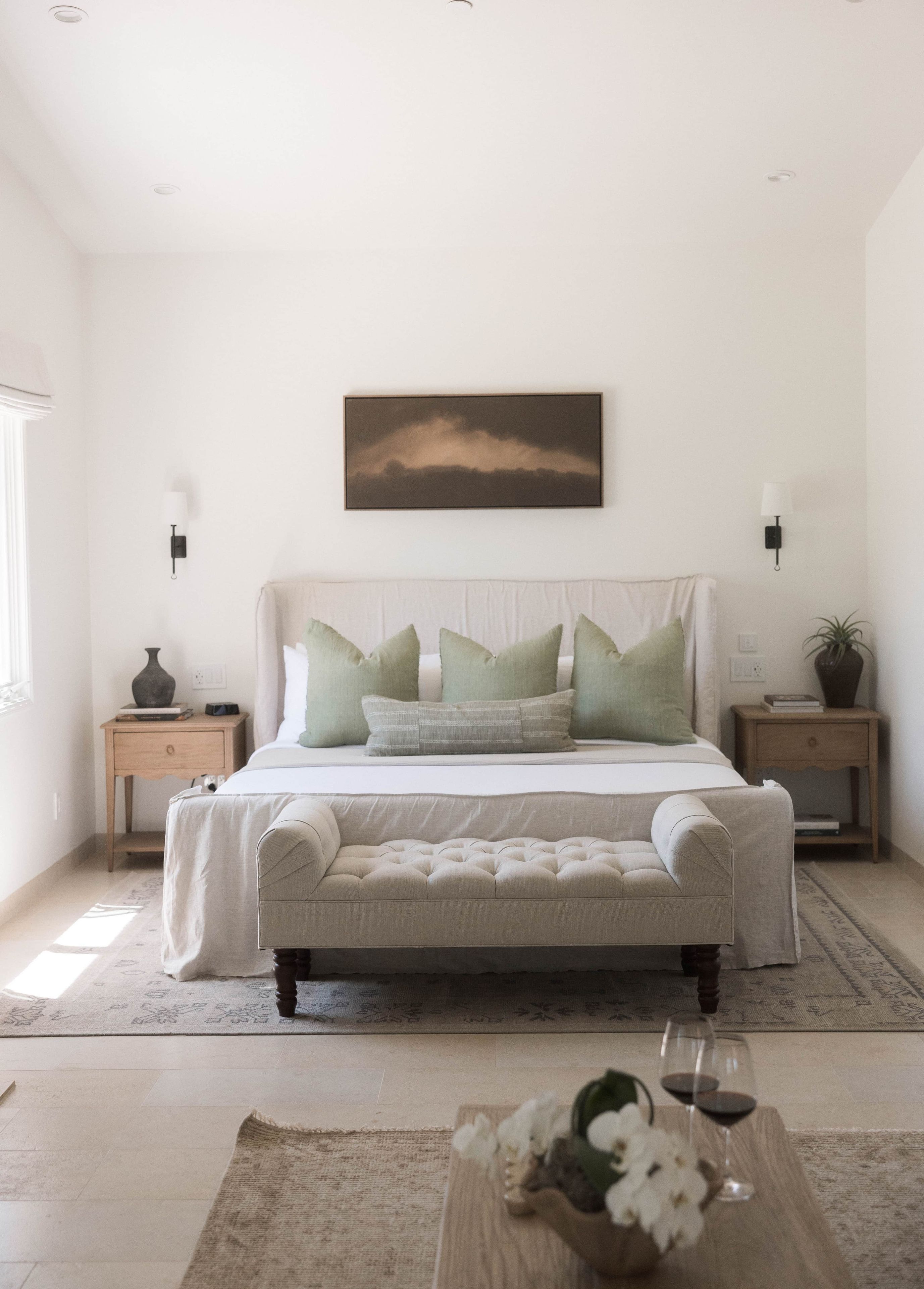 A bedroom with a bed, bedside tables, a wall-mounted picture, and a rug.