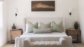 A bedroom with a bed, bedside tables, a wall-mounted picture, and a rug.