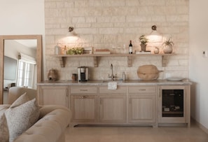 Una cocina con pared de piedra, armarios de madera, una cafetera y una botella de vino sobre la encimera.